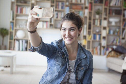 Junge Frau macht ein Selfie mit Smartphone zu Hause - RBF002872