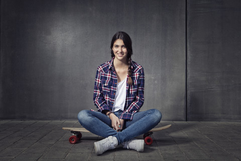 Junge Frau sitzt auf ihrem Longboard, lizenzfreies Stockfoto