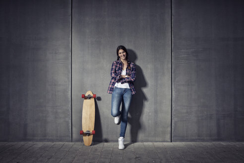 Junge Frau steht neben ihrem Longboard - RBF002882