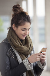 Porträt einer lächelnden jungen Frau mit Smartphone - RBF002887