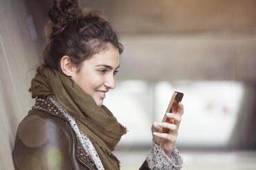 Lächelnde junge Frau mit Smartphone - RBF002890