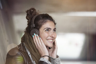 Portrait of smiling young woman hearing music with headphones - RBF002892
