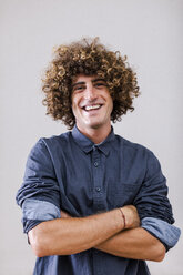 Portrait of smiling man with curly hair and crossed arms - EBSF000858