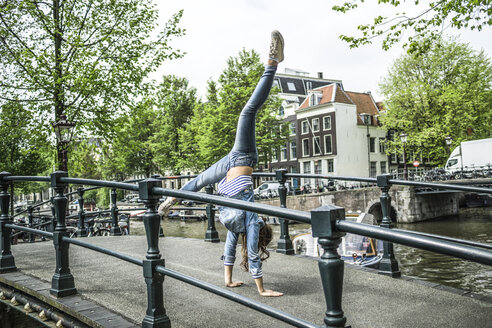 Niederlande, Amsterdam, Touristin im Handstand auf einer Fußgängerbrücke - RIBF000077