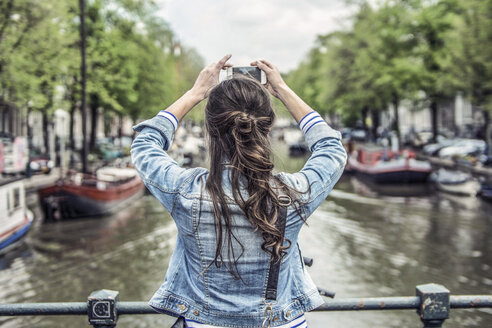 Niederlande, Amsterdam, weibliche Touristin macht ein Selfie mit Smartphone - RIBF000090