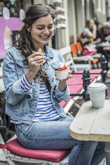 Niederlande, Amsterdam, weibliche Touristin sitzt in einem Straßencafé und isst gefrorenen Joghurt - RIBF000091