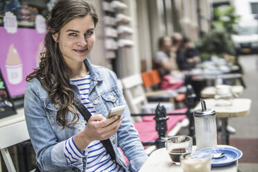 Netherlands, Amsterdam, portrait of female tourist sitting in a street cafe - RIBF000092