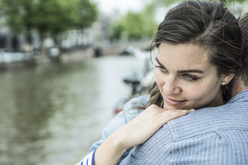 Niederlande, Amsterdam, Frau umarmt Mann vor der Gracht der Stadt - RIBF000094