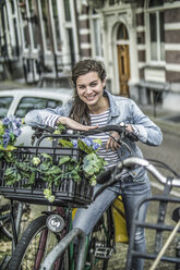 Netherlands, Amsterdam, smiling woman leaning on her bicycle - RIBF000095