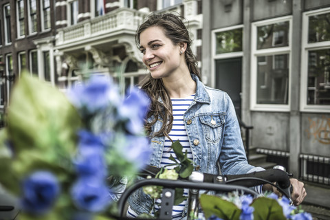 Niederlande, Amsterdam, lächelnde Frau mit Fahrrad, lizenzfreies Stockfoto