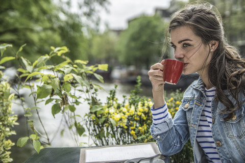 Niederlande, Amsterdam, Frau trinkt eine Tasse Kaffee in einem Straßencafé, lizenzfreies Stockfoto
