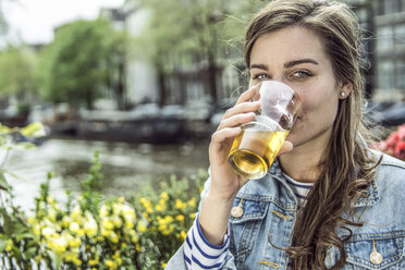 Netherlands, Amsterdam, woman drinking glass of beer in a street cafe - RIBF000106