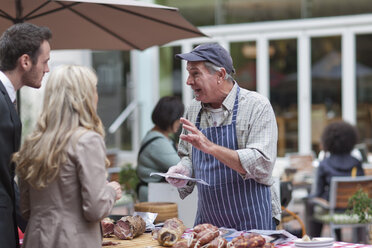 Man selling sausage at city market - ZEF007016