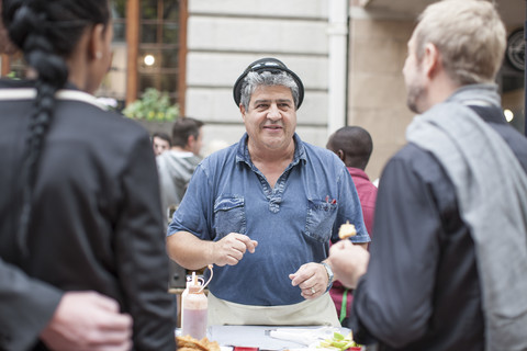 Lebensmittelverkäufer auf einem Markt in der Stadt bieten den Kunden Snacks an, lizenzfreies Stockfoto