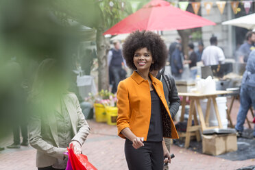 Smiling woman walking with suitcase in the city - ZEF006592