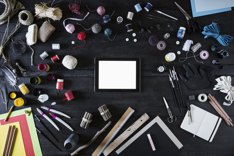 Arrangement of craft materials, tools and digital tablet on black wood stock photo