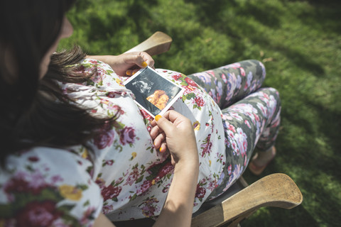 Schwangere Frau betrachtet Ultraschallbild, lizenzfreies Stockfoto