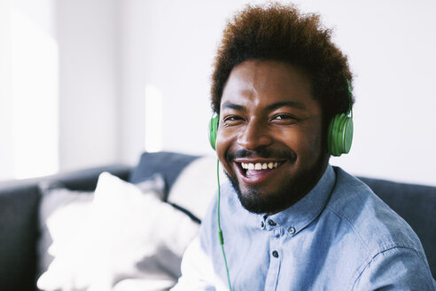 Junger afroamerikanischer Mann mit grünen Kopfhörern, lachend - EBSF000628