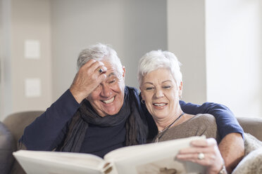 Senior couple watching photo album together - ZEF005510