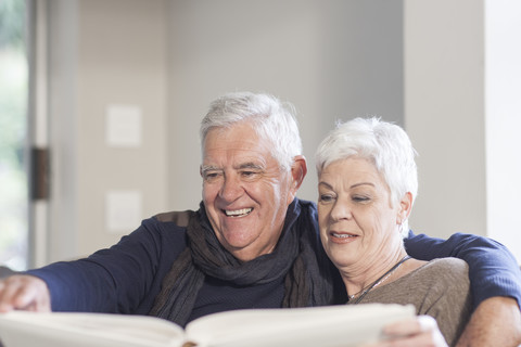 Älteres Paar schaut sich gemeinsam ein Fotoalbum an, lizenzfreies Stockfoto