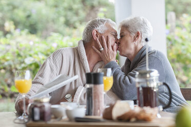Ältere Frau küsst ihren Mann am Frühstückstisch - ZEF005531