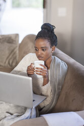 Young woman with laptop drinking coffee at home - ZEF005543