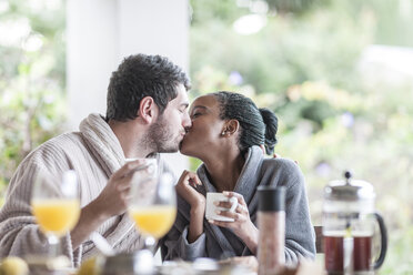 Kissing young couple at breakfast table - ZEF005558