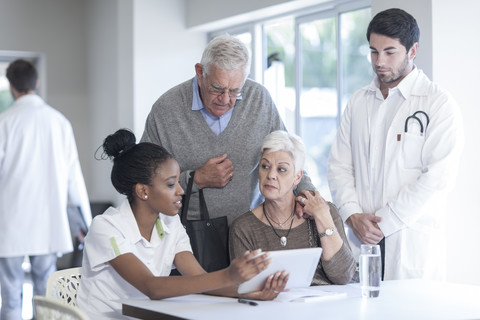 Älteres Ehepaar in der Klinik im Gespräch mit Arzt und Krankenschwester, lizenzfreies Stockfoto
