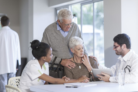 Älteres Ehepaar in der Klinik im Gespräch mit Arzt und Krankenschwester, lizenzfreies Stockfoto