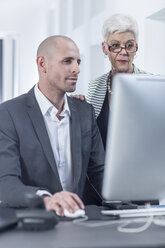 Businessman working on computer, senior woman on his side - ZEF005604