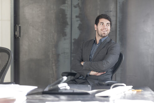 Businessman sitting at desk with arms crossed - ZEF005606