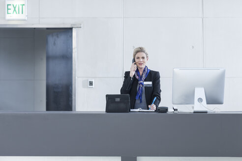 Frau hinter der Rezeption in der Hotellobby beim Telefonieren - ZEF005613