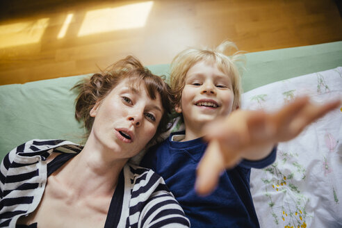Mutter und kleiner Sohn liegen auf dem Bett und strecken sich der Kamera entgegen - MFF001645