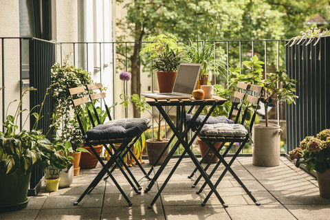 Bistro chairs and table with laptop on balcony stock photo