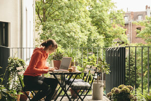 Woman using her laptop on balcony - MFF001653