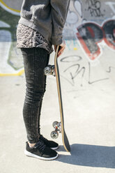 Female skate boarder leaning on skateboard - MGOF000258