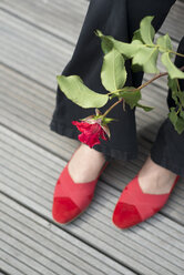 Frau mit roter Rose trägt ein Paar rote Schuhe - HLF000910
