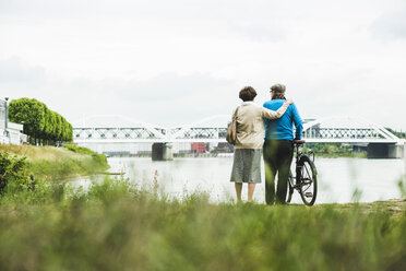 Rückenansicht eines älteren Paares am Wasser mit Fahrrad - UUF004495