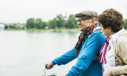 Senior couple with bicycle in front of water - UUF004497