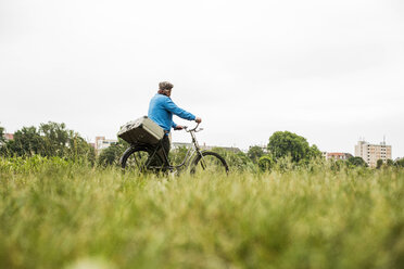 Senior man trasporting suitcase on his bicycle - UUF004521