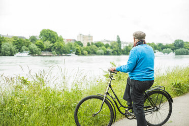 Älterer Mann mit Fahrrad schaut zum Fluss - UUF004526