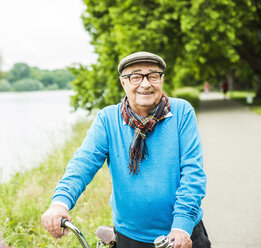 Porträt eines glücklichen älteren Mannes auf seinem Fahrrad - UUF004528