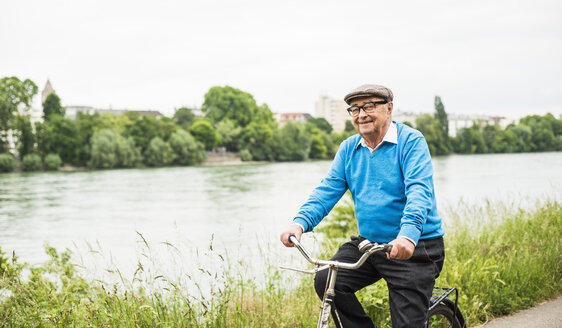 Lächelnder älterer Mann auf dem Fahrrad - UUF004540