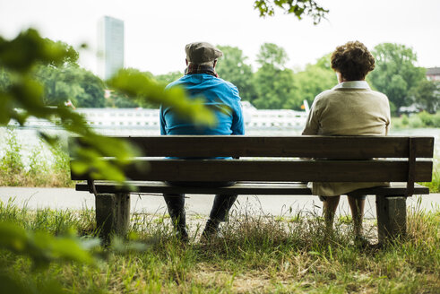 Back view of senior couple sitting on a bench - UUF004548