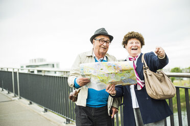 Senior couple with map standing on a bridge - UUF004551