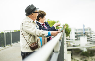 Älteres Paar mit Karte auf einer Brücke stehend mit Blick auf die Aussicht - UUF004552