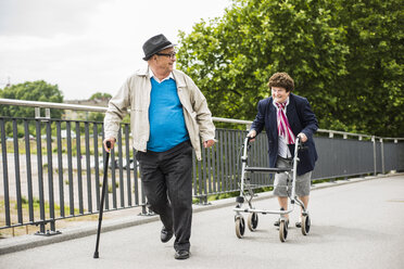 Senior couple with walking stick and wheeled walker - UUF004561