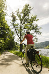 Deutschland, Cochem, Frau fährt mit dem Fahrrad am Moselufer entlang - UUF004569