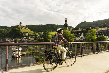 Germany, Cochem, cyclist passing bridge over Moselle - UUF004571