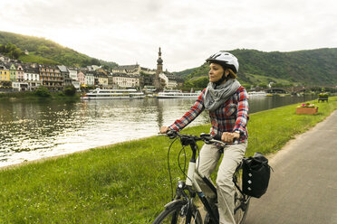 Deutschland, Cochem, Frau fährt mit dem Fahrrad am Moselufer entlang - UUF004583